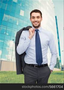 business and people concept - smiling young and handsome businessman over business centre background