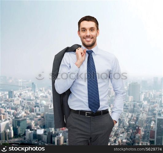 business and people concept - smiling young and handsome businessman over cityscape background