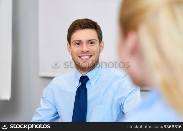 business and people concept - smiling young businessman talking to female colleague at office. businessman talking to female colleague at office