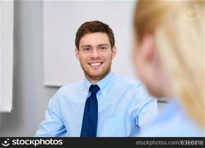 business and people concept - smiling young businessman talking to female colleague at office. businessman talking to female colleague at office