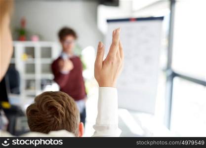 business and people concept - woman raising hand at presentation in office. woman raising hand at presentation in office