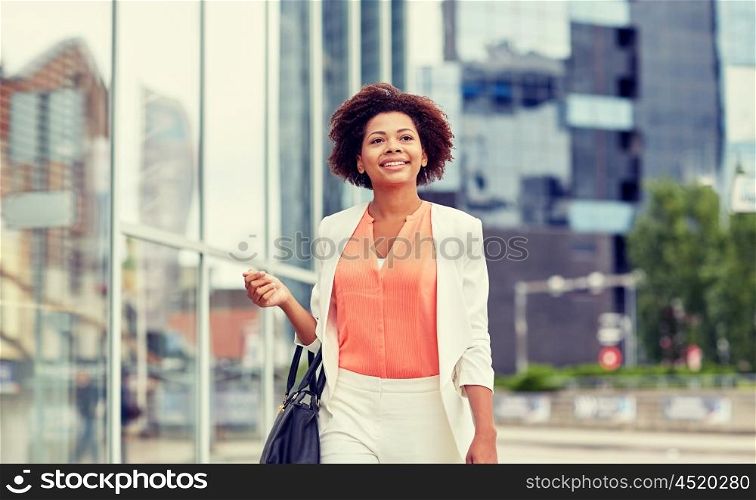 business and people concept - young smiling african american businesswoman in city. happy young african american businesswoman in city