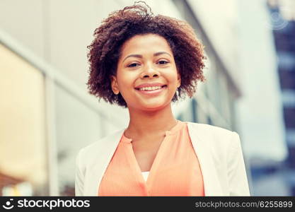 business and people concept - young smiling african american businesswoman in city. happy young african american businesswoman in city