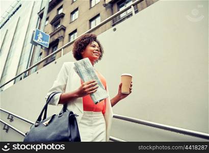 business and people concept - young smiling african american businesswoman with coffee cup going down stairs into city underpass. happy african businesswoman with coffee in city