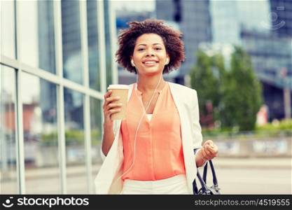 business and people concept - young smiling african american businesswoman with coffee cup in city. happy african businesswoman with coffee in city