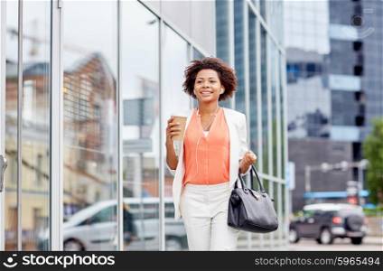 business and people concept - young smiling african american businesswoman with coffee cup in city. happy african businesswoman with coffee in city