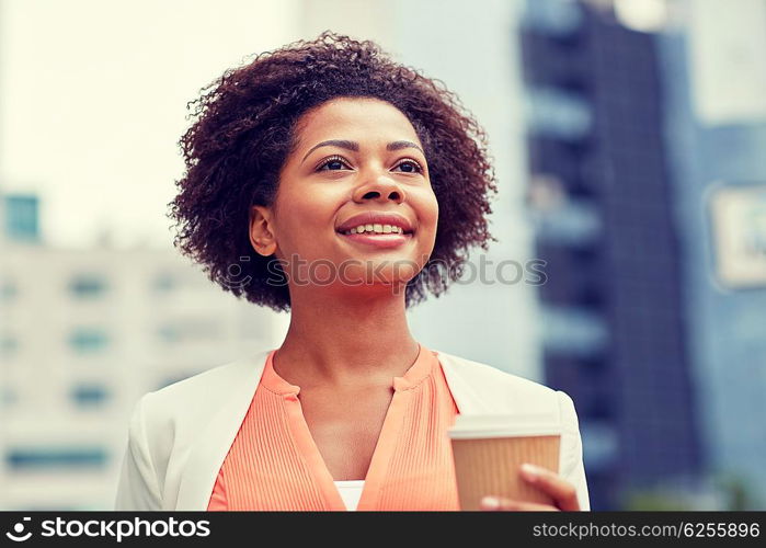 business and people concept - young smiling african american businesswoman with coffee cup in city. happy african businesswoman with coffee in city