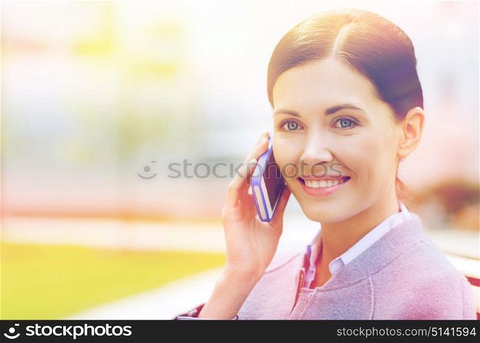 business and people concept - young smiling businesswoman calling on smartphone in city. young smiling businesswoman calling on smartphone
