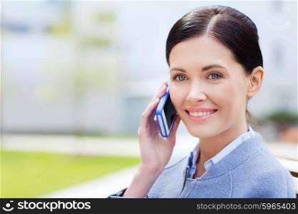 business and people concept - young smiling businesswoman calling on smartphone in city. young smiling businesswoman calling on smartphone