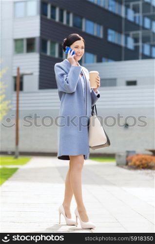 business and people concept - young smiling businesswoman calling on smartphone over office building. happy businesswoman calling on smartphone in city