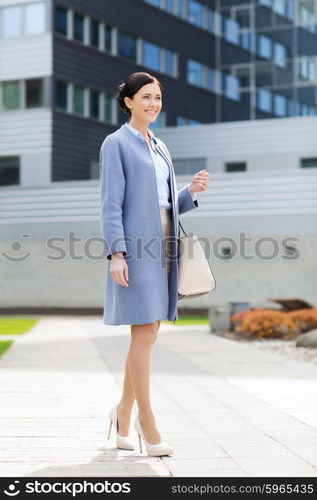 business and people concept - young smiling businesswoman over office building. young smiling businesswoman over office building