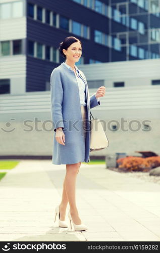 business and people concept - young smiling businesswoman over office building. young smiling businesswoman over office building