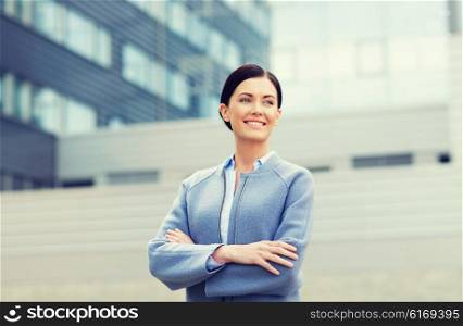 business and people concept - young smiling businesswoman over office building. young smiling businesswoman over office building