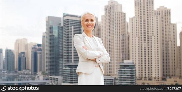 business and people concept - young smiling businesswoman with crossed arms over dubai city background. young smiling businesswoman with crossed arms
