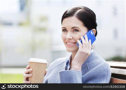 business and people concept - young smiling woman calling on smartphone and drinking coffee in city. smiling woman with coffee calling on smartphone