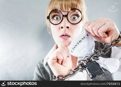 Business and stress concept. Furious businesswoman in glasses with chained hands holding contract grunge background unusual angle view