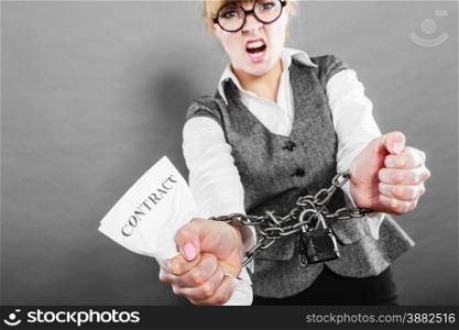 Business and stress concept. Furious businesswoman in glasses with chained hands holding contract grunge background