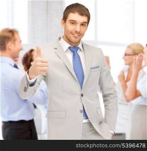 business and success - happy businessman showing thumbs up in office