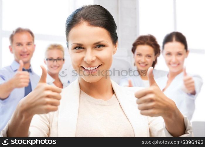 business and success - happy businesswoman showing thumbs up in office