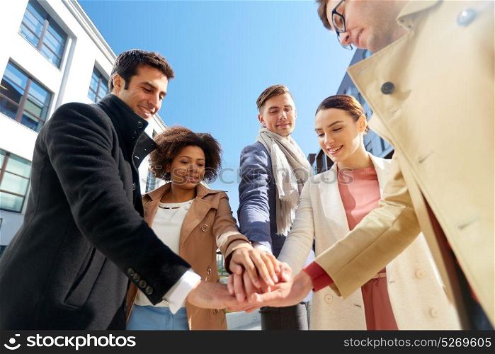 business and teamwork concept - international group of people holding hands together on city street. group of happy people holding hands in city