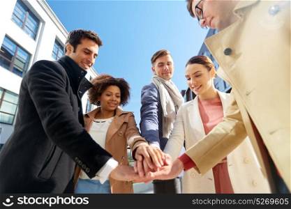 business and teamwork concept - international group of people holding hands together on city street. group of happy people holding hands in city