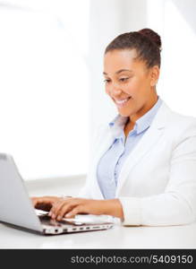 business and technology concept - african businesswoman with laptop in office