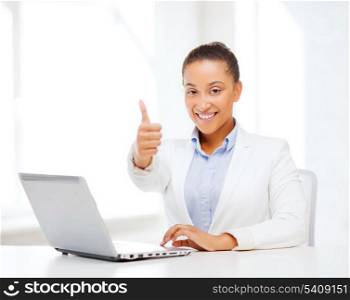business and technology concept - african businesswoman with laptop in office showing thumbs up