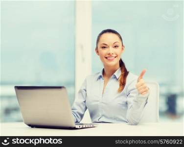 business and technology concept - businesswoman with laptop in office showing thumbs up