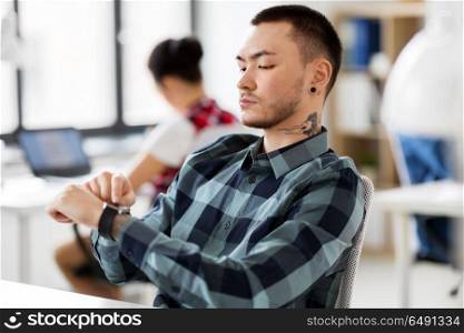 business and technology concept - man with laptop computer and smart watch working at office. creative man with smart watch working at office. creative man with smart watch working at office