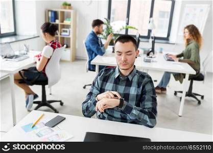 business and technology concept - man with smartwatch working at office. creative man with smartwatch working at office. creative man with smartwatch working at office