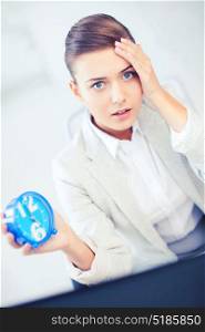 business and time management concept - stressed businesswoman holding clock. stressed businesswoman holding clock