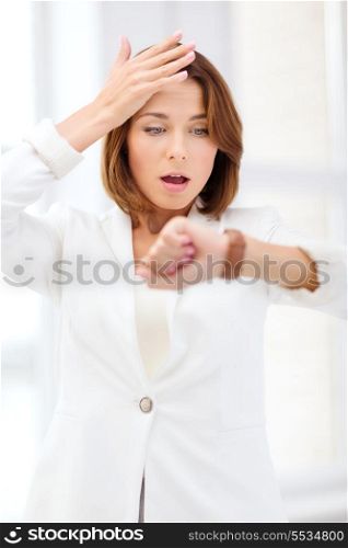 business and time management concept - stressed businesswoman looking at wrist watch in office