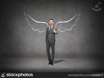 business, angel investor, safety, security and people concept - smiling young businessman with wings drawing showing thumbs up over gray concrete background