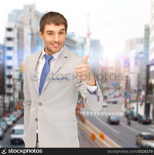business, architecture and building concept - handsome businessman showing thumbs up