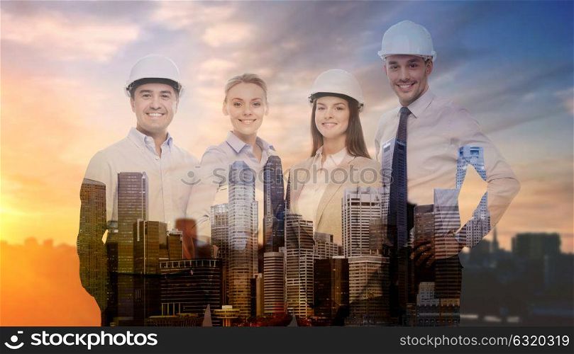 business, architecture and building concept - happy team of architects in white hard hats over city background with double exposure. business team in white hard hats
