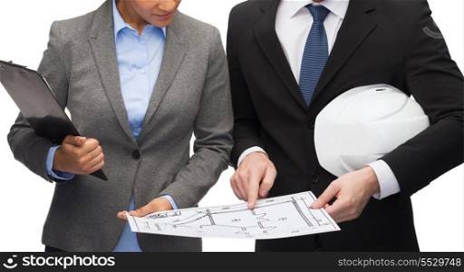 business, architecture and development concept - businesswoman and businessman with clipboard and white helmet pointing finger to blueprint