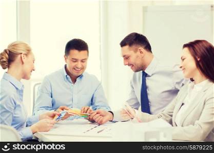 business, architecture and office concept - happy team of architects and designers with color samples in office