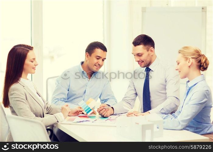 business, architecture and office concept - happy team of architects and designers with color samples in office