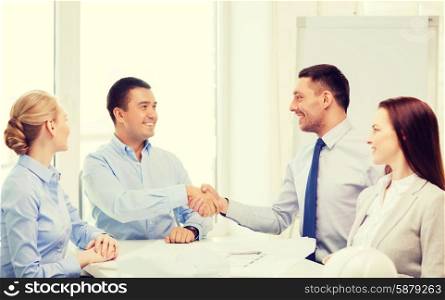 business, architecture and office concept - happy team of architects and designers in office shaking hands