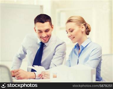 business, architecture and office concept - smiling businessman and businesswoman looking at color samples at office
