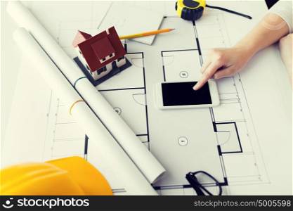 business, architecture, building, construction and people concept - close up of architect hand with living house blueprint and smarphone. close up of hand with blueprint and smartphone