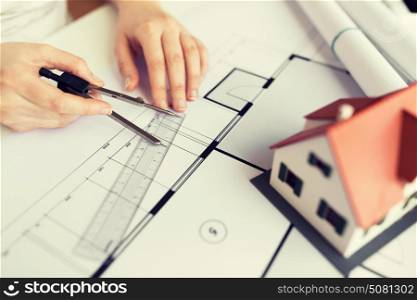 business, architecture, building, construction and people concept - close up of architect hands with compass and ruler measuring living house blueprint. close up of hands with compass measuring blueprint