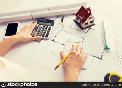 business, architecture, building, construction and people concept - close up of architect hand with blueprint counting on calculator. close up of architect hand counting on calculator