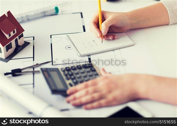 business, architecture, building, construction and people concept - close up of architect hand with blueprint and architectural tools writing to notebook. close up of hand on blueprint writing to notebook