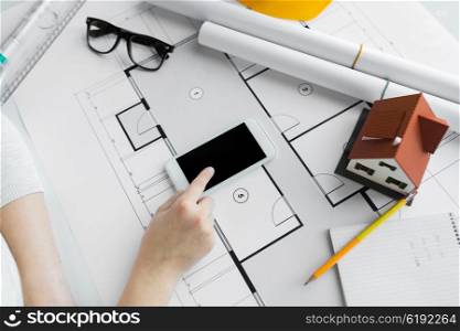 business, architecture, building, construction and people concept - close up of architect hand with living house blueprint and smarphone