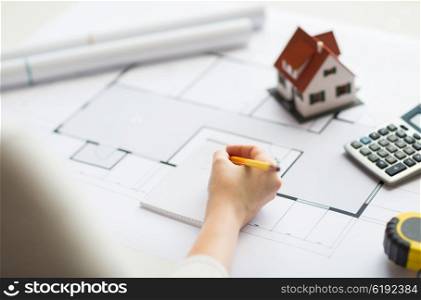 business, architecture, building, construction and people concept - close up of architect hand with blueprint and architectural tools writing to notebook
