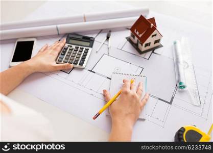 business, architecture, building, construction and people concept - close up of architect hand with blueprint counting on calculator