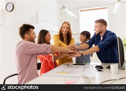 business, architecture, teamwork and people concept - happy international creative architect team or students with blueprint putting hands on top together at office. creative team holding hands together at office