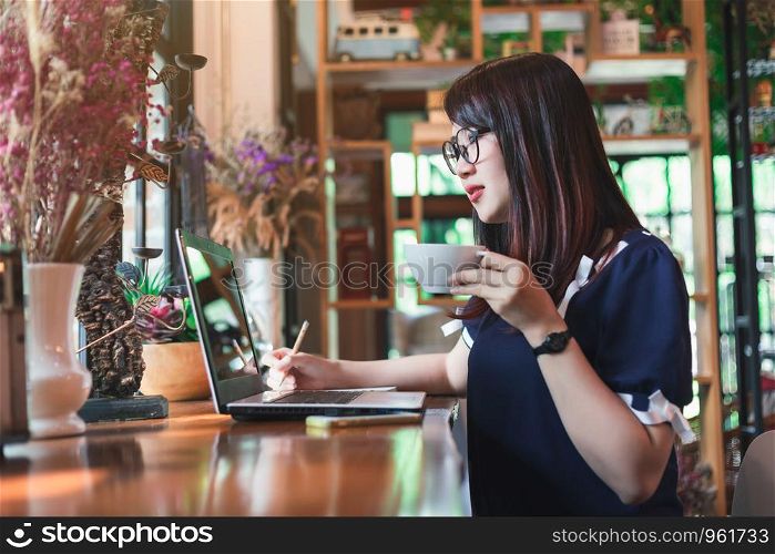 Business Asian woman hold cup of coffee working with laptop computer on in coffee shop like the background.