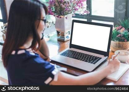 Business Asian woman hold pick up Smartphone make a note and working with laptop with blank white screen computer on in coffee shop like the background.